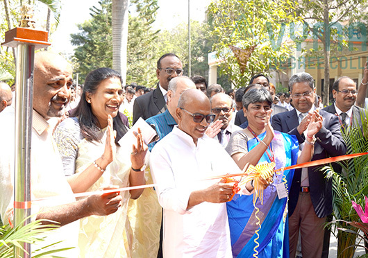 A grand inauguration ceremony at Vymak Degree College with dignitaries cutting the ribbon and a joyful audience applauding