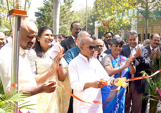 A grand inauguration ceremony at Vymak Degree College with dignitaries cutting the ribbon and a joyful audience applauding